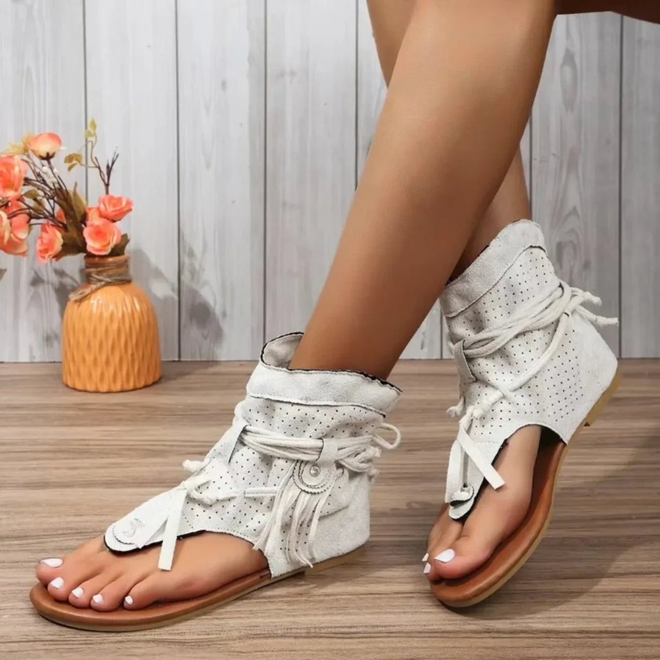 White wedge sandals with lace-up design worn by a person on a wooden floor.